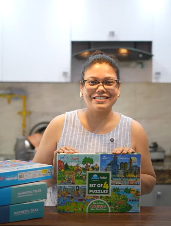 Mom holding magnetic tiles and puzzle toys recommended for toddlers
